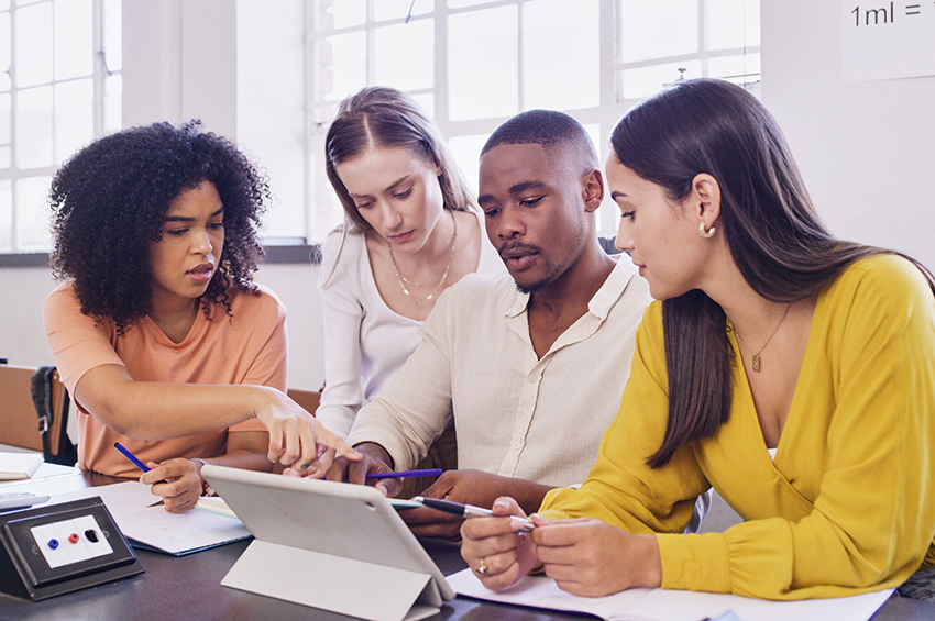 Group of employees reviewing information on a tablet.