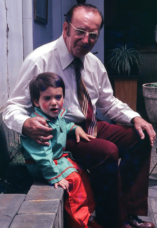 Carlos Zuluaga as a child sitting on a stoop with his grandfather, Antonio