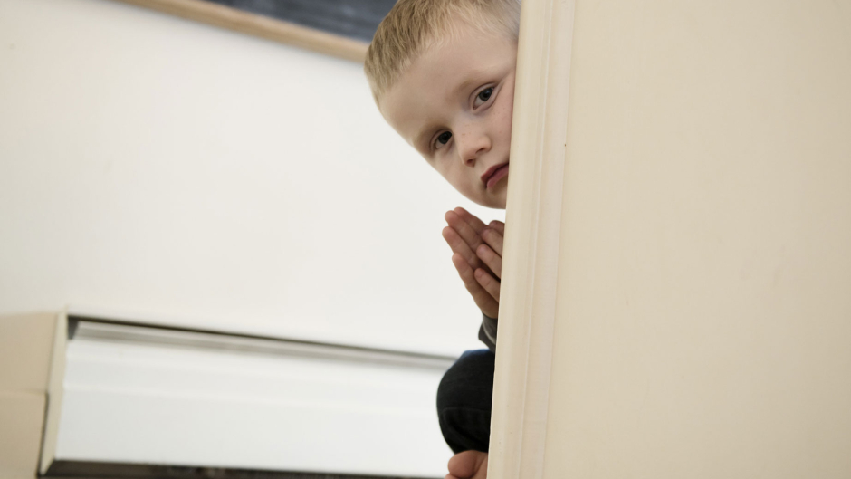 a child peaking around a doorframe