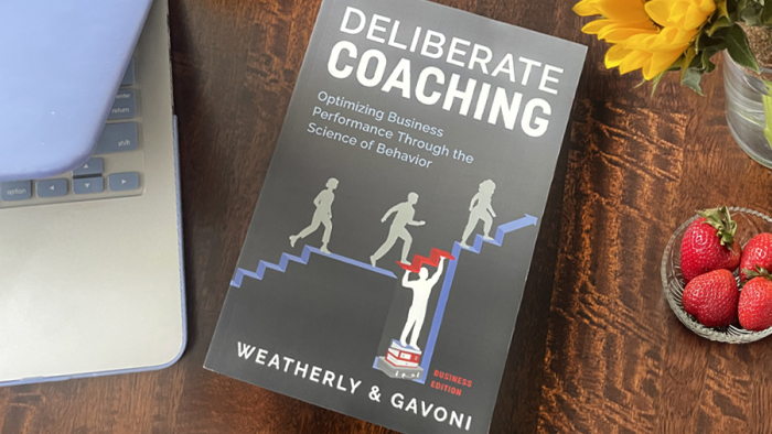 Deliberate Coaching Business Edition next to laptop on desk